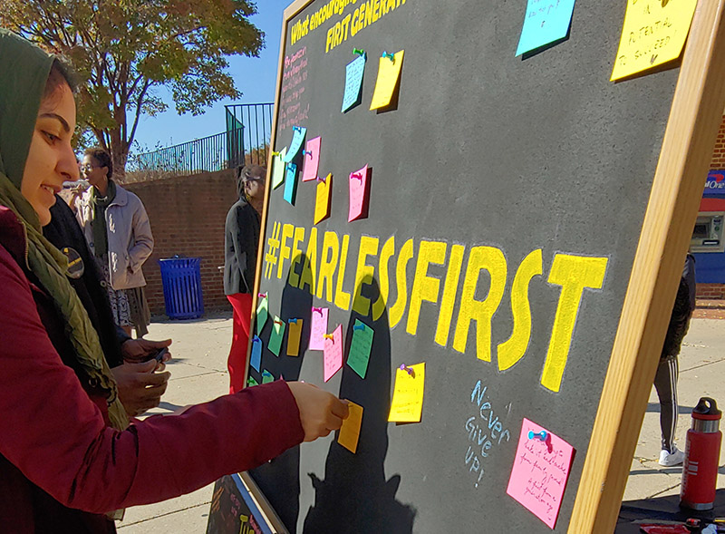 student puts postit note on board